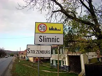 Inscripție bilingvă româno-germană la intrarea dintr-un sat din Transilvania (Slimnic)