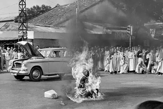 a monk sat cross legged in the middle of a road, covered in large flames