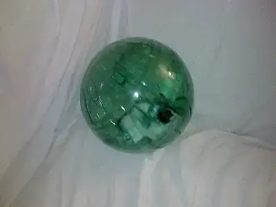Photo of a white hamster in a transparent green plastic hamster ball