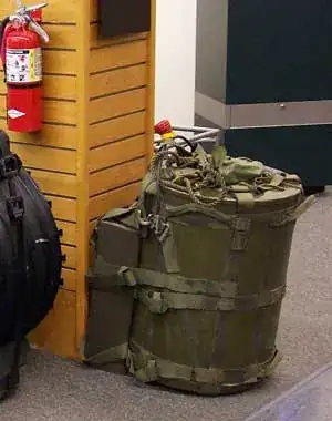 A backpack with a W54 nuke inside, propped against a column. A fire extinguisher is present for size comparison.